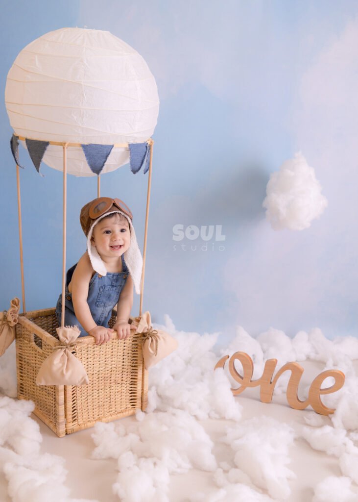 one year old first birthday cake smash baby toddler hot air balloon setup clouds blue sky photography photoshoot photo session