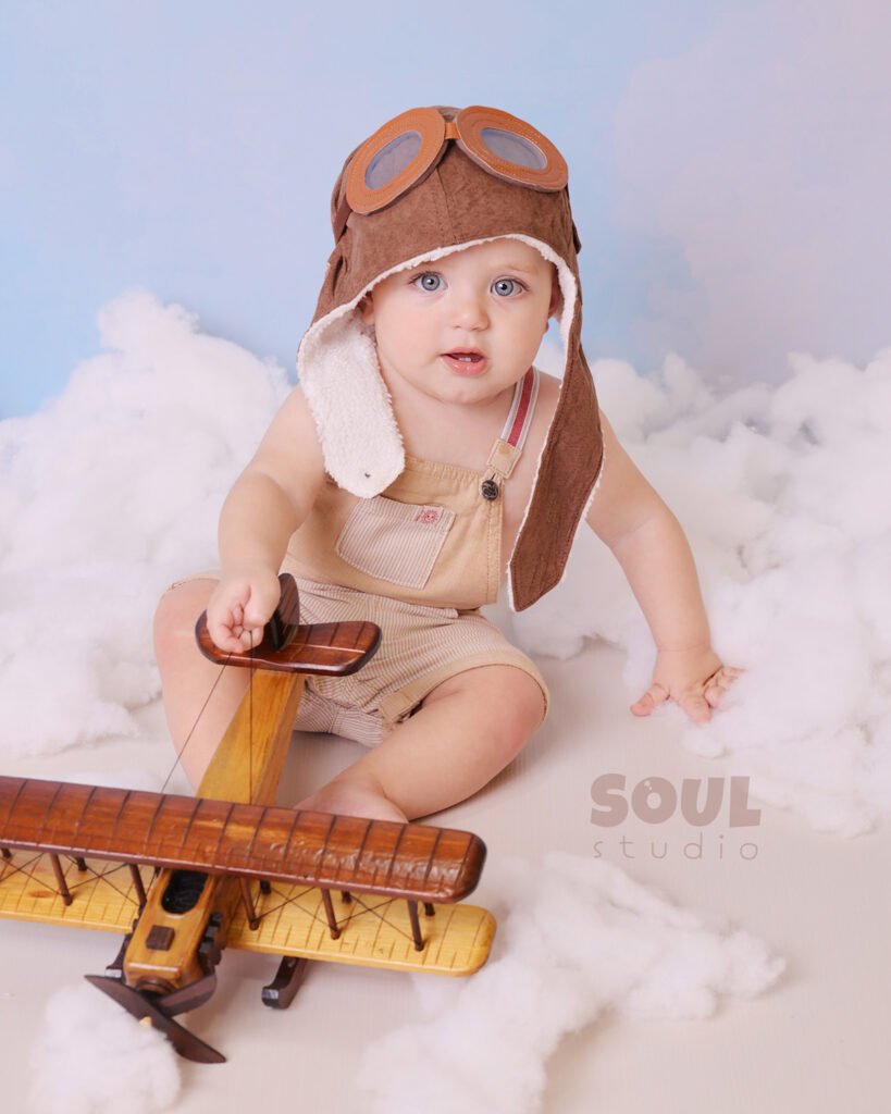 airplane baby sitter sky clouds 1 year old aviator hat pilot blue boy