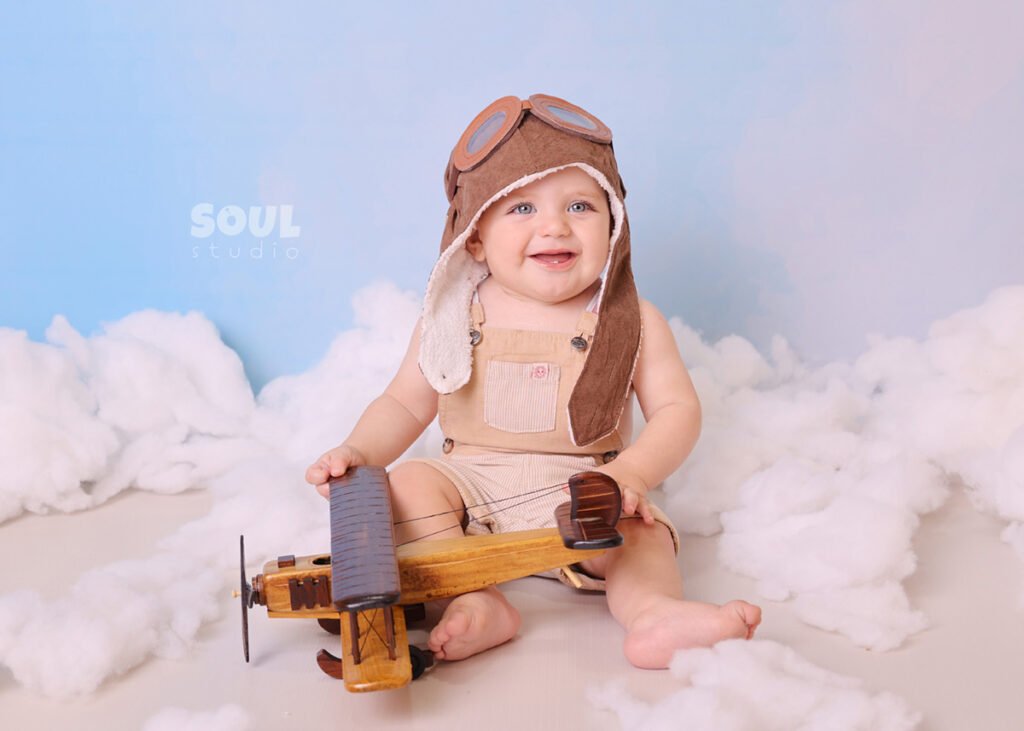 airplane baby sitter sky clouds 1 year old aviator hat pilot blue boy