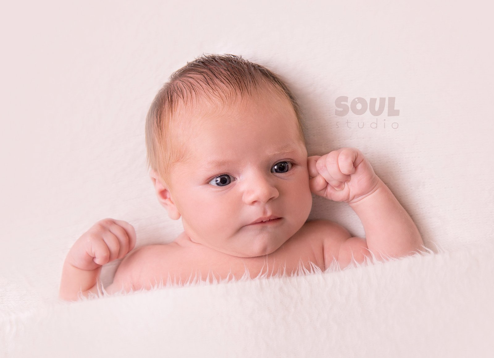 Awake newborn resting on a soft cream blanket at Soul Studio, Amman