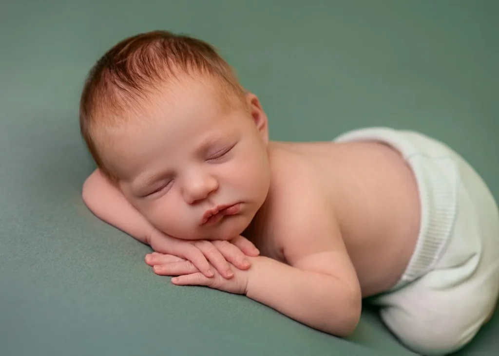 Sleeping newborn posed on a sage green backdrop at Soul Studio, Amman