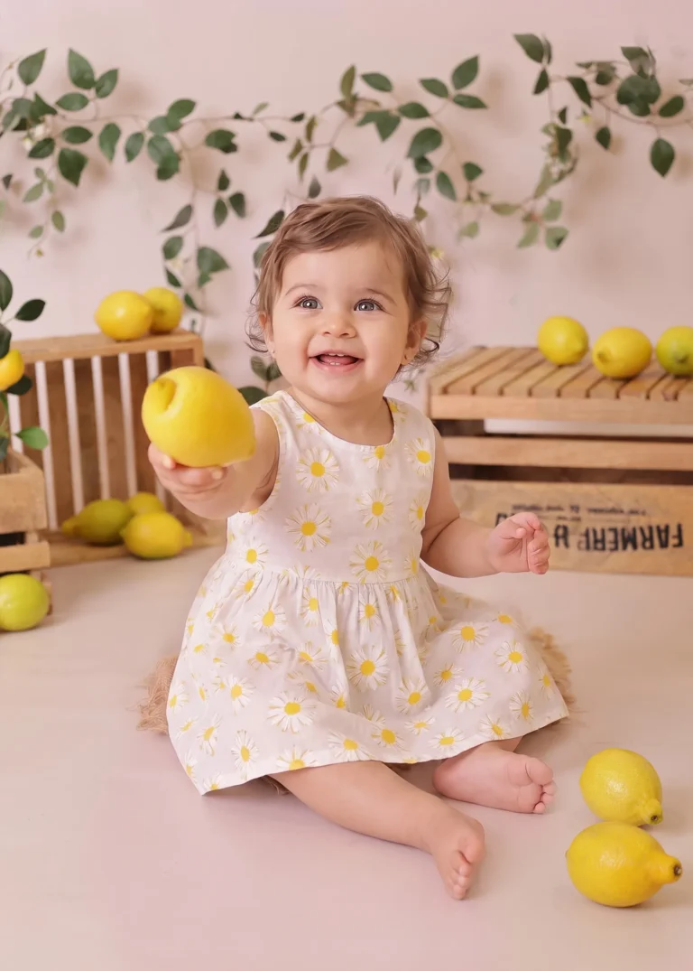 Smiling baby girl holding a lemon in a styled lemon-season setup