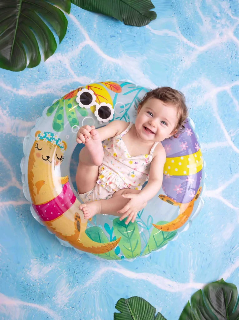 Laughing baby in a floral swimsuit floating in a swim ring at Soul Studio